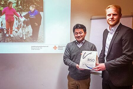 Der Bürgermeister von Arita und Werkstattleiter Michael Druch überreichen sich Gastgeschenke.