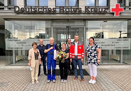 Sieben Personen, darunter das Ehepaar Richter, stehen mit einem Strauß Blumen vor dem Eingang des DRK Landesverbandes Sachsen 