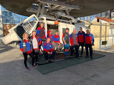 Jugendliche von der DRK Bergwacht in Sachsen sind zu Besuch im Bergwachtzentrum in Bad Tölz. Sie posieren vor einem Hubschrauber.