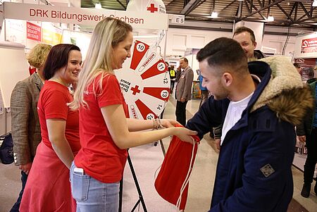 Ein Besucher dreht am Glücksrad am Messestand des Bildungswerkes. Er darf einen Preis ziehen.